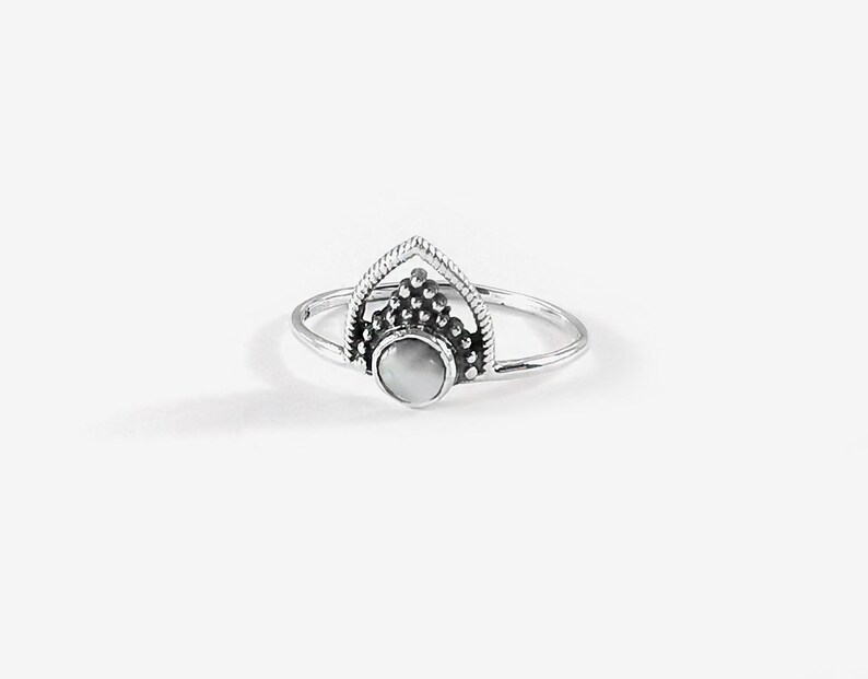 May include: A silver ring with a white stone set in a geometric design.