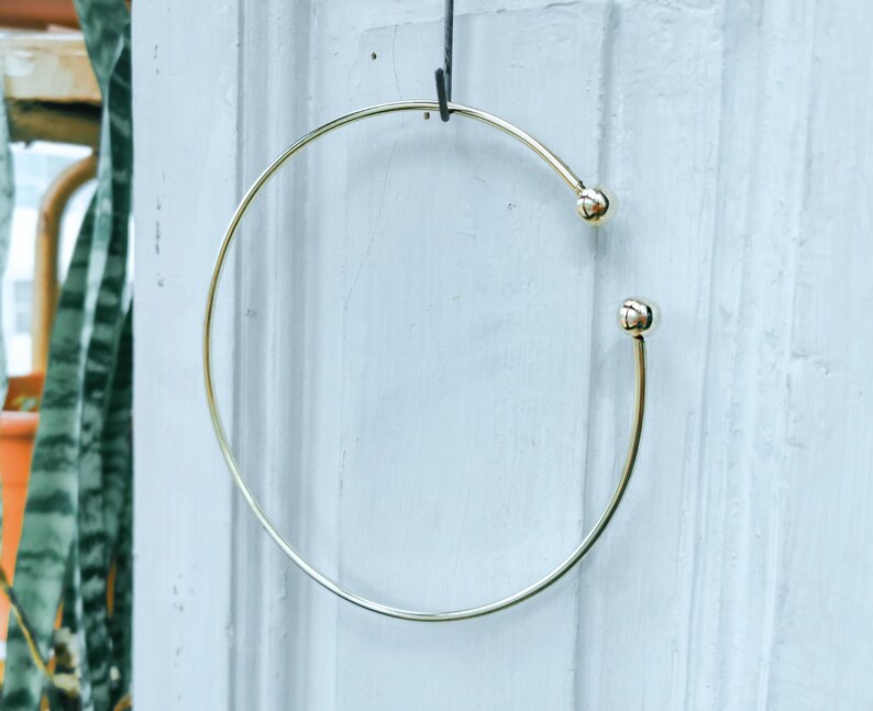 May include: A gold-toned bangle bracelet with two small round balls on the ends.