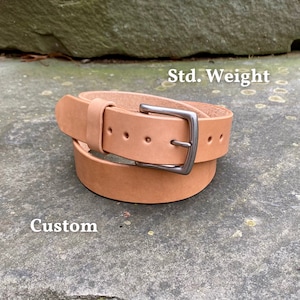 May include: A light brown leather belt with a silver buckle. The belt is rolled up and the text "Std. Weight" and "Custom" are visible.