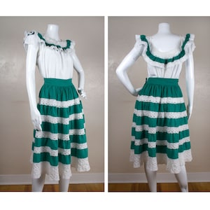May include: A green and white skirt with white lace trim. The skirt is gathered at the waist and has a flared silhouette. The skirt is made of a lightweight fabric and is perfect for summer.