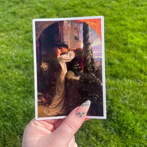 May include: A vintage-style sticker featuring a painting of a couple embracing in a romantic setting. The painting is set against a backdrop of a castle with a column and a sunset sky.
