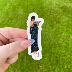 May include: A sticker featuring a painting of a woman in a blue dress holding a bowl with water pouring out.