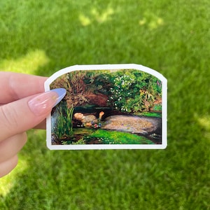 May include: A sticker featuring a painting of a woman lying in a stream of water surrounded by lush greenery and flowers.