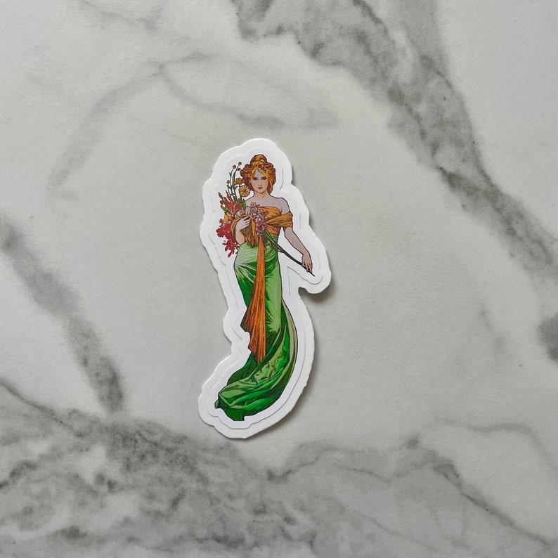 May include: A sticker featuring a woman in a green and gold dress holding a bouquet of flowers. The woman is standing on a white background.