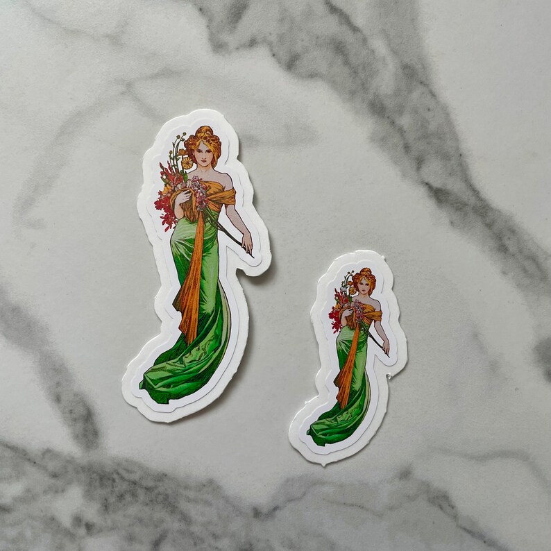 May include: Two vintage-style stickers featuring women in green dresses with floral bouquets. The larger sticker shows a woman holding a long, thin object, possibly a wand or a stick. The smaller sticker shows a woman holding a smaller bouquet.