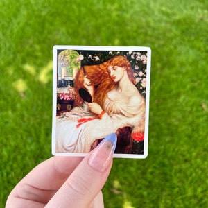 May include: A sticker featuring a painting of a woman with long red hair, wearing a white dress, sitting in a chair and looking into a mirror. The background is a garden with flowers.