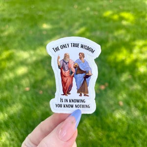 May include: White sticker with a black border featuring a painting of two men. The text reads "The only true wisdom is in knowing you know nothing."