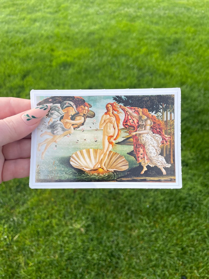 May include: A vintage-style print of the famous Renaissance painting "The Birth of Venus" by Sandro Botticelli. The painting depicts a nude woman standing on a giant scallop shell, with the wind blowing her hair and a flowing drapery.