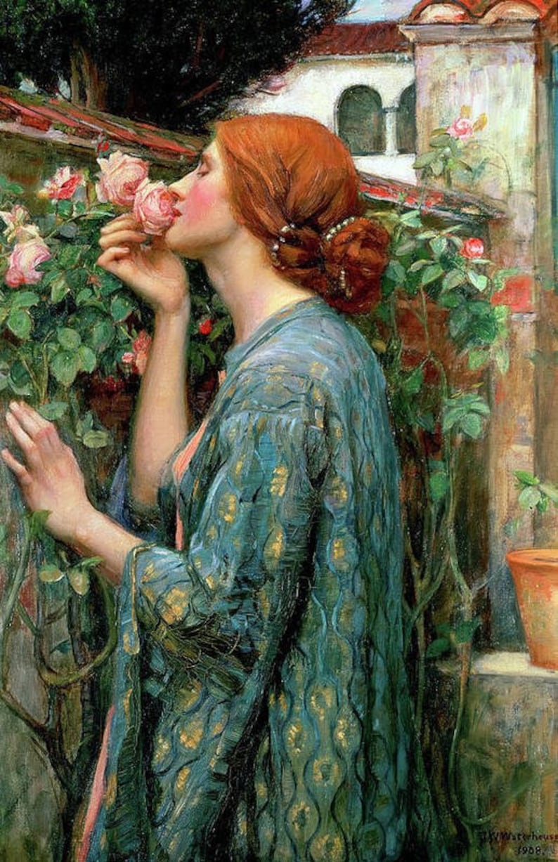 May include: A woman with long red hair is wearing a blue and gold patterned robe. She is smelling a pink rose in a garden setting.