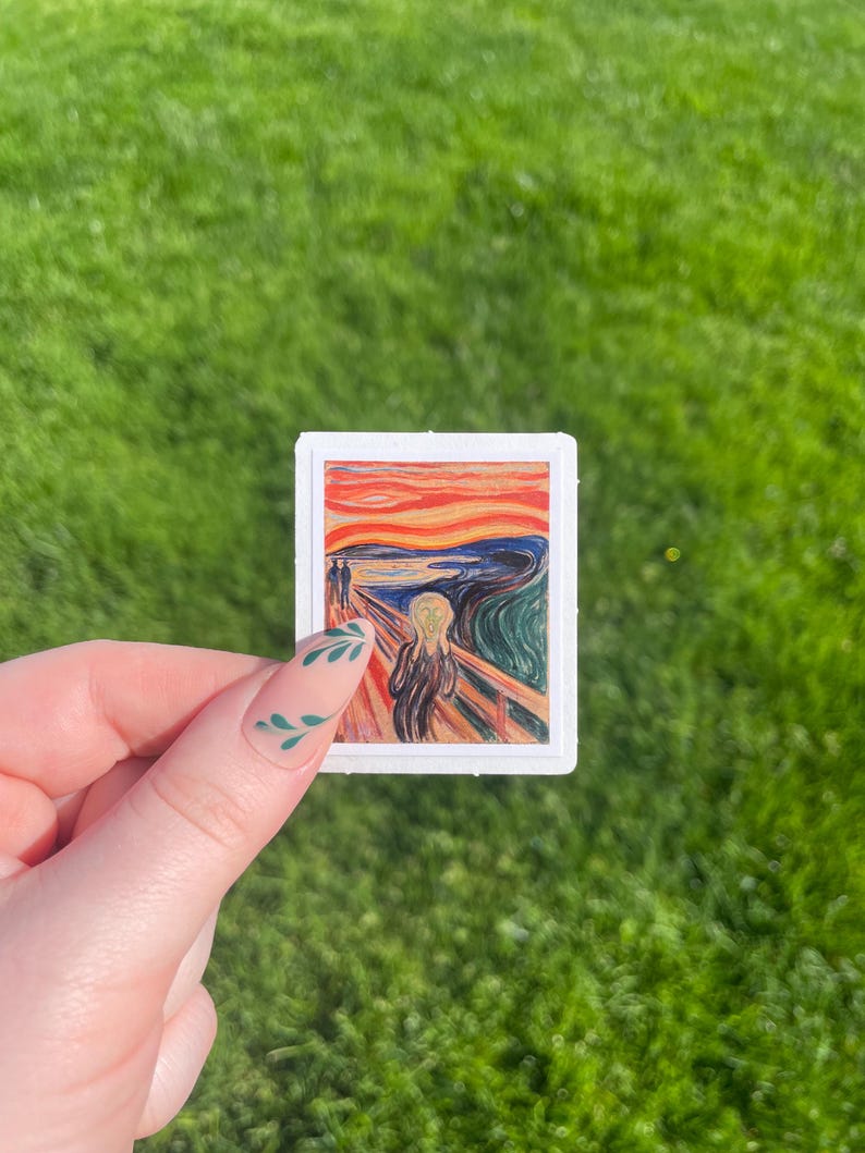 May include: A sticker featuring a reproduction of Edvard Munch's iconic painting "The Scream". The painting depicts a figure with a distorted face and a bright, swirling sky.