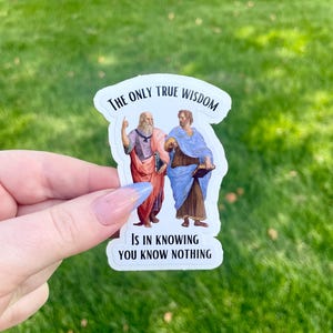 May include: White sticker with a quote from Socrates and Plato. The quote reads "The only true wisdom is in knowing you know nothing". The sticker features illustrations of Socrates and Plato.
