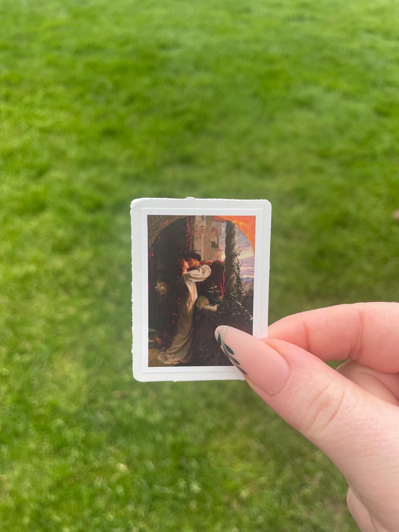 May include: A sticker featuring a painting of a woman in a white dress standing in a doorway with a man behind her. The painting is set against a backdrop of a castle and a sunset.
