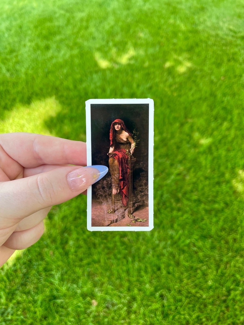 May include: A vintage sticker featuring a painting of a woman in a red robe holding an olive branch. The woman is standing on a pedestal with a broken chain at her feet.