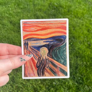 May include: A sticker featuring a reproduction of Edvard Munch's famous painting "The Scream". The painting depicts a figure with a distorted face screaming against a swirling, red and orange sky.