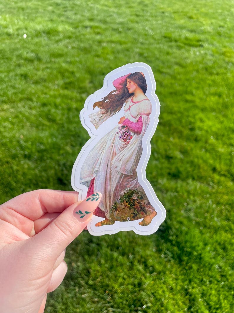 May include: A sticker featuring a vintage illustration of a woman in a white dress with pink accents, holding a bouquet of flowers. Her hair is flowing in the wind. The sticker is on a green grassy background.