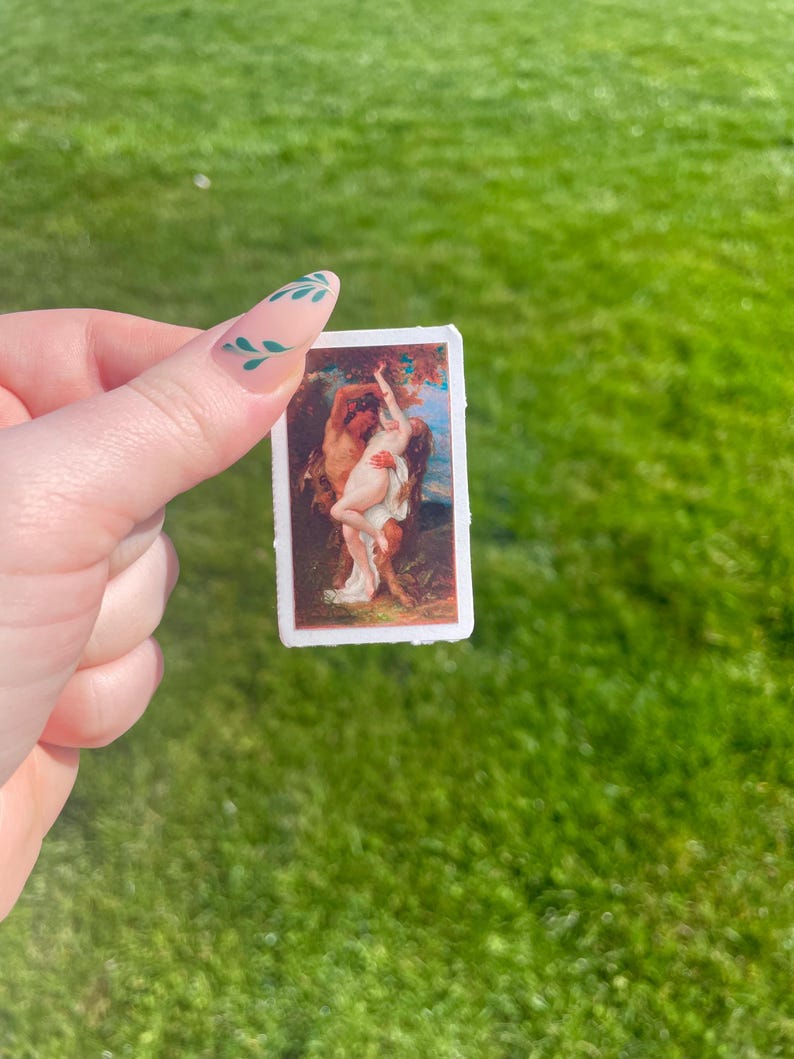Op de afbeelding: Een sticker met een vintage schilderij van een stel dat elkaar omarmt in een bosrijke omgeving. Het schilderij is in romantische stijl met warme kleuren en een zachte, dromerige sfeer.
