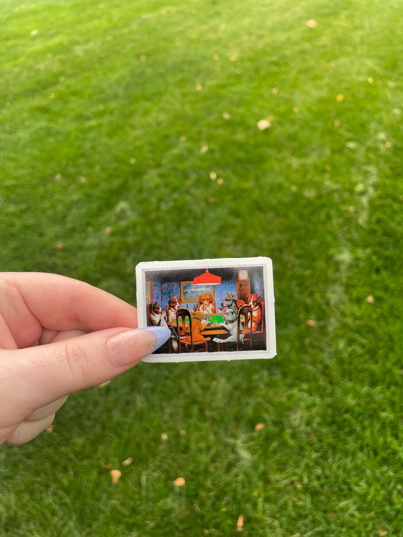 May include: A sticker featuring a painting of dogs playing cards around a green table. The dogs are wearing clothes and have human-like expressions. The painting is set in a room with a red lampshade and a clock on the wall.