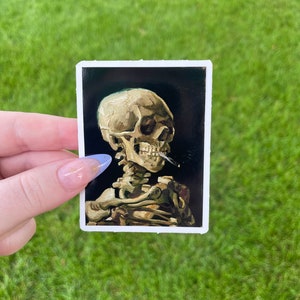 May include: A sticker featuring a painting of a human skeleton with a skull. The skeleton is depicted in a dark background with a yellow-toned light.