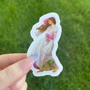 May include: A sticker featuring a vintage illustration of a woman in a white dress with pink accents, holding a bouquet of flowers. The woman's hair is flowing in the wind. The sticker is on a green background.
