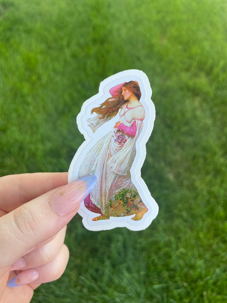 May include: A sticker featuring a vintage illustration of a woman in a white dress with pink accents, holding a bouquet of flowers. The woman's hair is flowing in the wind. The sticker is on a green background.