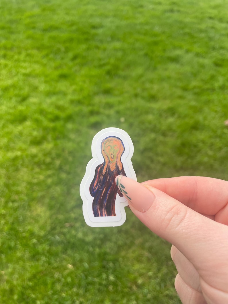 Puede incluir: Una pegatina con la pintura "El Grito" de Edvard Munch. La obra representa una figura con la boca abierta y las manos en la cara, sobre un cielo arremolinado naranja y azul. La pegatina tiene un borde blanco.
