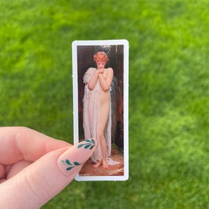 May include: A rectangular sticker depicting a classical painting of a nude figure with red hair, draped in a sheer cloth. The artwork is set against a backdrop of a waterfall and foliage.