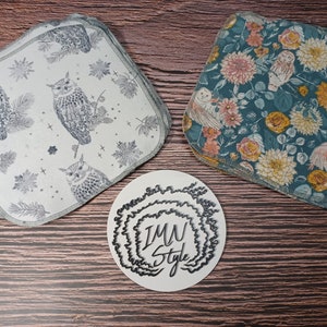 May include: Two sets of fabric squares with different patterns. One set is white with a gray owl pattern and the other is teal with a floral pattern. A white circle with the text "IMW Style" in black is in the center of the image.