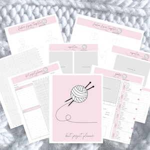 Peut inclure: Plusieurs pages roses et blanches d'un planificateur de projets de tricot, dont des pages "fashion figure template" et "yarn". La page centrale présente un graphique de fil et d'aiguilles avec le texte "knit project planner". Les pages sont disposées sur une surface blanche texturée.