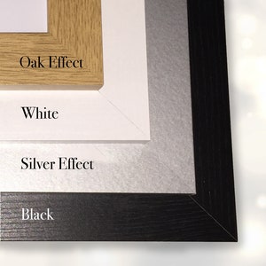 May include: A layered display of picture frame samples. The top frame is oak effect, followed by white, silver effect, and black frames. Each frame is labeled with its color or finish.