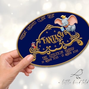May include: An oval-shaped sign with a navy blue background and gold lettering. The sign features the word "FANTASY" in ornate script, along with an illustration of Dumbo the elephant. The text "WHERE DREAMS COME TRUE" is arched at the top.