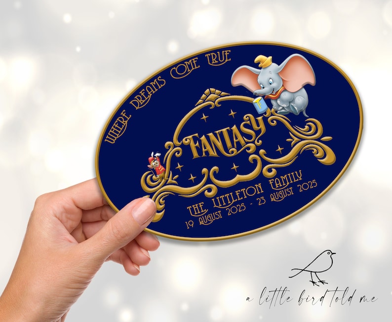 Pu&ograve; includere: Un cartello ovale con sfondo blu navy e scritte dorate. Il cartello presenta la parola "FANTASY" in scrittura ornata, insieme a un'illustrazione di Dumbo l'elefante. Il testo "WHERE DREAMS COME TRUE" &egrave; arcuato nella parte superiore.