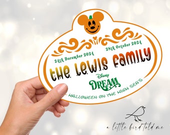 May include: A white and orange pumpkin-shaped Disney Cruise Line name tag with Mickey Mouse ears and a pumpkin face. The text reads "the Lewis FAMILY" with the dates "24th December 2024" and "28th October 2024". The text "Disney DREAM HALLOWEEN ON THE HIGH SEA'S" is also included.