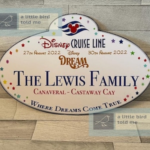 Puede incluir: Un cartel blanco ovalado con un borde azul y estrellas de colores. El cartel dice "Disney Cruise Line" con las fechas "27 de agosto de 2022" y "30 de agosto de 2022". El cartel tambi&eacute;n dice "Disney Dream" y "The Lewis Family" con la ubicaci&oacute;n "Canaveral - Castaway Cay". El cartel termina con la frase "Where Dreams Come True".