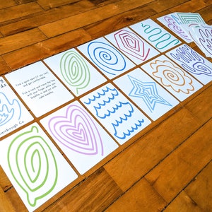 May include: A set of finger tracing calming cards with various shapes and patterns, including a heart, a star, waves, and spirals. The cards are white with colorful lines and the text "Finger Tracing Calming Cards" and "Wainbough Co."
