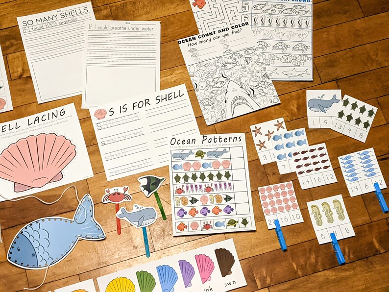 May include: A set of printable ocean-themed educational activities for children. The set includes a counting and colouring page, a pattern matching activity, a lacing activity, a writing activity, and a set of counting cards. The activities feature images of sea creatures such as whales, fish, seahorses, and seashells.