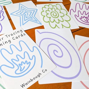 May include: Set of finger tracing cards with various shapes and designs, including a star, flower, spiral, and hand. The cards are white with blue, green, purple, and pink lines. The text on the cards reads "Finger Tracing Calming Cards" and "Wainbough Co."