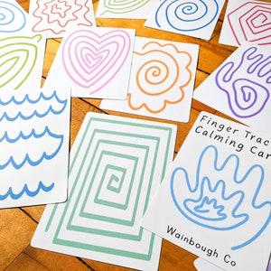 May include: A set of colorful finger tracing cards with various shapes and patterns, including waves, hearts, spirals, and squares. The cards are labeled "Finger Tracing Calming Cards" and "Wainbough Co."