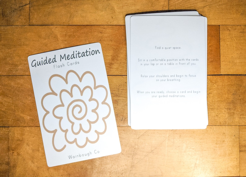 May include: A set of guided meditation flash cards with a brown flower design on the front. The back of the cards has instructions for using the cards, including finding a quiet space, relaxing your shoulders, and focusing on your breathing. The cards are labelled "Guided Meditation Flash Cards" and "Wainbough Co."