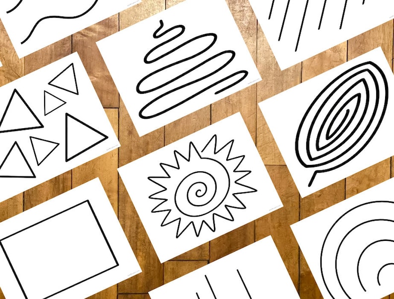 May include: A collection of white cards with black line drawings of various shapes and patterns, including triangles, rectangles, spirals, and wavy lines. The cards are arranged on a wooden surface.