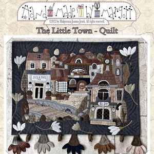 Puede incluir: Una colcha que representa una pequeña ciudad con edificios, árboles y flores. La colcha mide 62 cm por 69,5 cm y se titula "The Little Town - Quilt".