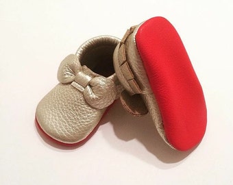 Mocasines de bebé de piel con suela roja y lazo platino, hechos a mano