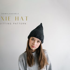 Könnte beinhalten: Ein herunterladbares Strickmuster für eine Pixie-Mütze. Das Muster wird an einem Modell gezeigt, das einen grauen Pullover und eine schwarze Pixie-Mütze trägt.