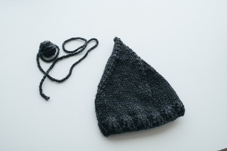 May include: A dark gray knitted hat with a ball of yarn and a length of yarn.
