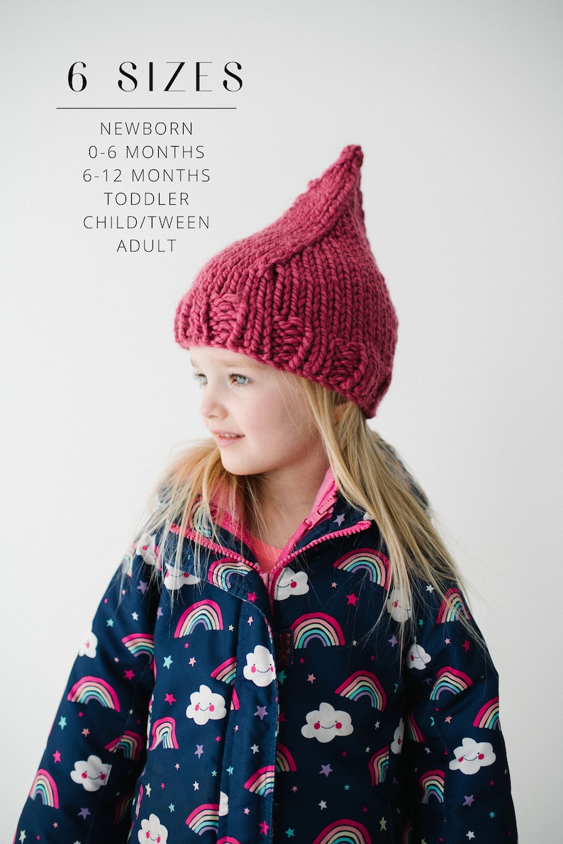 May include: A pink knitted hat with a pointed top. The hat is being worn by a young child with blonde hair. The child is wearing a blue jacket with a rainbow and cloud pattern. The text "6 SIZES" is written at the top of the image. The text below "6 SIZES" reads "NEWBORN, 0-6 MONTHS, 6-12 MONTHS, TODDLER, CHILD/TWEEN, ADULT."