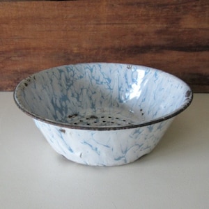 May include: A white enamel colander with a blue marbled pattern and a metal strainer. The colander is slightly chipped around the rim.