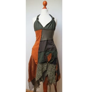 Op de afbeelding: Een patchwork halterjurk in bruin, groen en oranje tinten. De jurk heeft een gelaagde rok met een kant-overlay en een bloemenapplicatie.