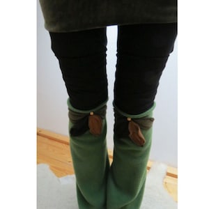 Puede incluir: Calentadores de piernas de forro polar verde con adornos de hojas de fieltro marrón y negro.