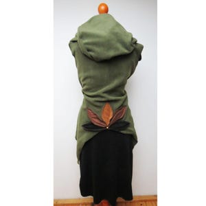 Pode incluir: Vestido verde com capuz e saia preta. O vestido apresenta um design floral decorativo nas costas com detalhes em castanho, preto e dourado. O vestido é feito de tecido macio e tem um design único e fluido.