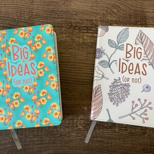 Pode incluir: Dois diários em branco com o texto "Big Ideas (or not)" na capa. Um diário tem uma capa turquesa com um padrão floral amarelo. O outro diário tem uma capa branca com um padrão floral colorido.