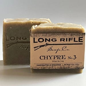 May include: Two bars of green artisan soap with a brown label that reads "LONG RIFLE Soap Co. CHYPRE No. 3 Artisan Bar Soap HANDCRAFTED IN WISCONSIN | Net Weight 4.5oz. (127g.)"